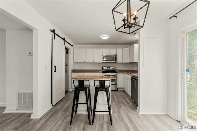 15241 Broadwater Cir, Chesterfield, VA 23831 - kitchen with appliances with stainless steel finishes, a barn door, light wood finished floors, and a kitchen breakfast bar