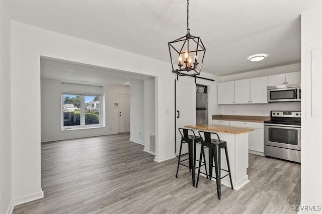 15241 Broadwater Cir, Chesterfield, VA 23831 - kitchen with appliances with stainless steel finishes, a breakfast bar, white cabinets, light wood-style floors, and a kitchen island