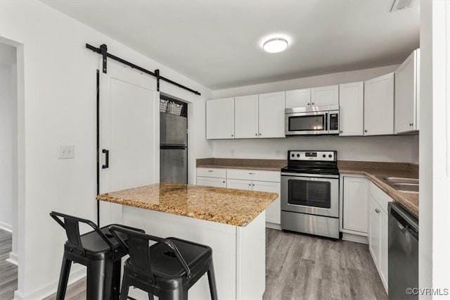 15241 Broadwater Cir, Chesterfield, VA 23831 - kitchen featuring stainless steel appliances, light wood-style floors, a barn door, and white cabinetry