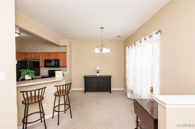 405 Hollybrook Ridge Ln, Richmond, VA 23223 - kitchen with black appliances, a breakfast bar, brown cabinets, hanging light fixtures, and a chandelier