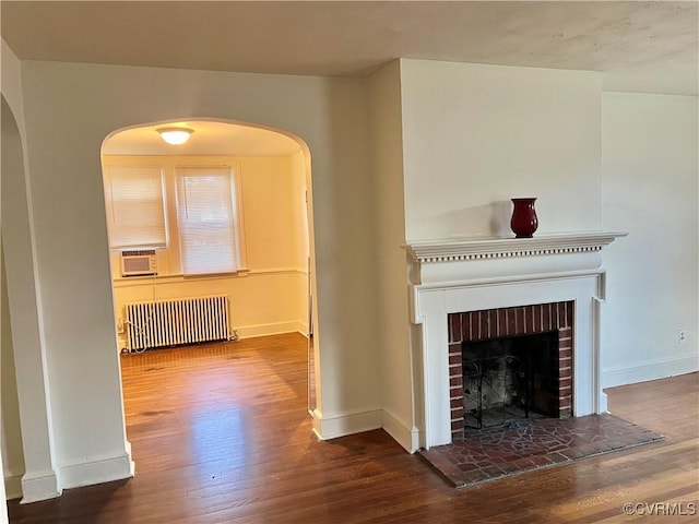 3305 Jeter Ave, Richmond, VA 23222 - unfurnished living room featuring radiator, arched walkways, wood finished floors, a fireplace, and cooling unit