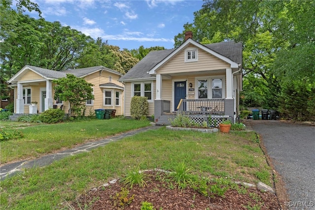 1708 Westwood Ave, Richmond, VA 23227 - bungalow-style home featuring covered porch, a chimney, a front lawn, and asphalt driveway