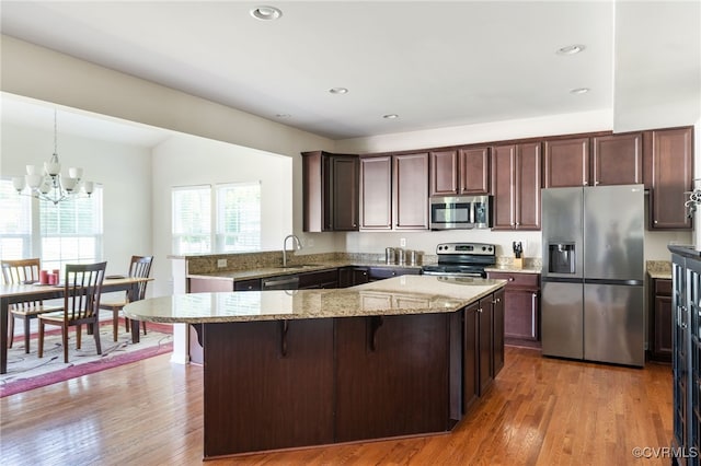 11012 Wingstem Ct, Glen Allen, VA 23060 - kitchen featuring appliances with stainless steel finishes, light stone countertops, a kitchen breakfast bar, wood finished floors, and a chandelier
