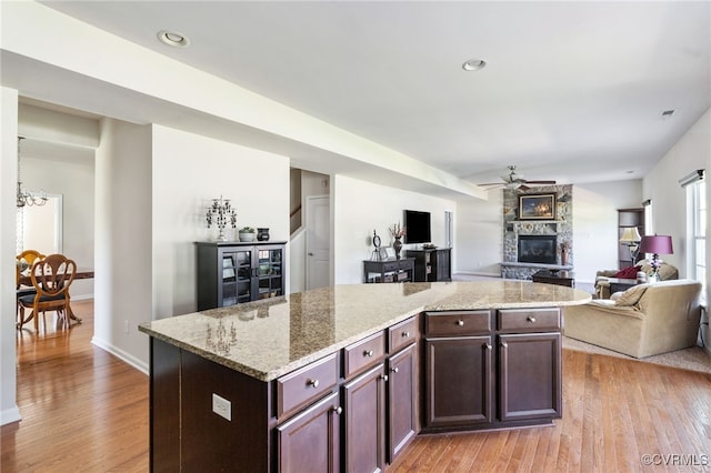 11012 Wingstem Ct, Glen Allen, VA 23060 - kitchen with a ceiling fan, light wood-style floors, a stone fireplace, open floor plan, and a kitchen island