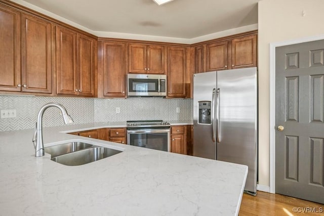 4133 San Marco Dr Unit 4133, Glen Allen, VA 23060 - kitchen with appliances with stainless steel finishes, brown cabinets, decorative backsplash, light stone counters, and light wood-type flooring