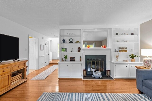 4855 Cypress Point Cir Unit 104, Virginia Beach, VA 23455 - living area with light wood-type flooring, a glass covered fireplace, built in shelves, and a textured ceiling