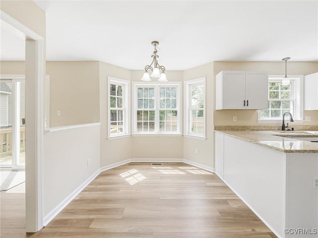 12213 Collinstone Pl, Glen Allen, VA 23059 - kitchen with light stone countertops, decorative light fixtures, light wood-style floors, white cabinets, and a chandelier