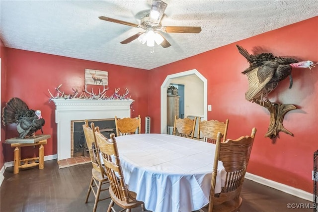1305 Pea Ridge Rd, King & Queen, VA 23023 - dining space with a textured ceiling, ceiling fan, a fireplace, wood finished floors, and arched walkways
