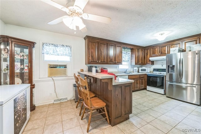 1305 Pea Ridge Rd, King & Queen, VA 23023 - kitchen with white appliances, under cabinet range hood, a peninsula, light tile patterned flooring, and a textured ceiling