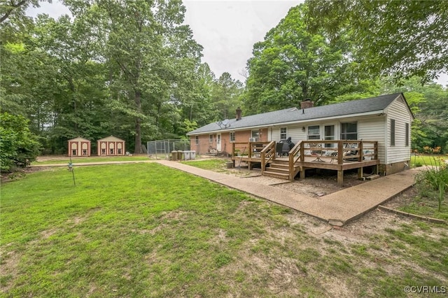 1305 Pea Ridge Rd, King & Queen, VA 23023 - back of property featuring a yard, a deck, a storage shed, a chimney, and view of scattered trees