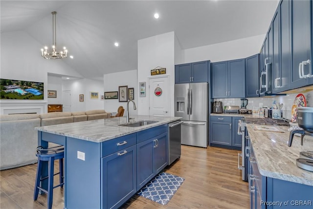 12 Essie Ct, Irvington, VA 22480 - kitchen with appliances with stainless steel finishes, blue cabinetry, open floor plan, a kitchen bar, and light wood finished floors