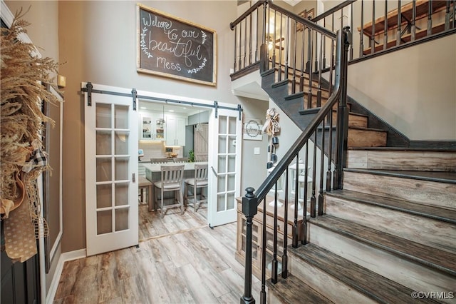 1442 Dorset Rd, Powhatan, VA 23139 - stairs featuring a barn door, french doors, a high ceiling, and wood finished floors