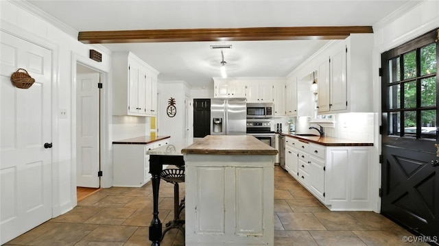 2711 Salisbury Rd, Midlothian, VA 23113 - kitchen featuring appliances with stainless steel finishes, beamed ceiling, white cabinetry, a kitchen island, and backsplash