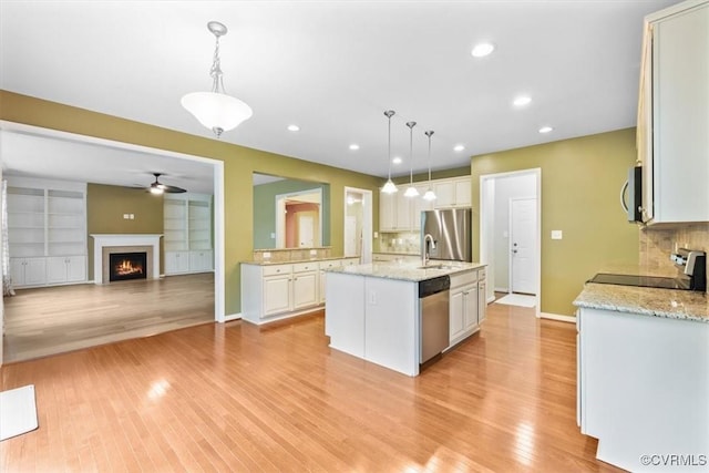 8738 New Holland Ln, Mechanicsville, VA 23116 - kitchen featuring appliances with stainless steel finishes, a warm lit fireplace, backsplash, light wood-type flooring, and recessed lighting