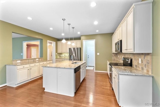 8738 New Holland Ln, Mechanicsville, VA 23116 - kitchen with stainless steel appliances, decorative backsplash, an island with sink, light wood-type flooring, and decorative light fixtures