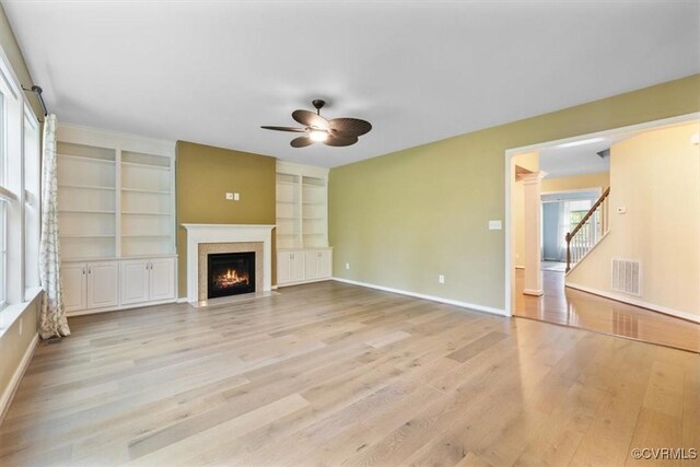 8738 New Holland Ln, Mechanicsville, VA 23116 - unfurnished living room featuring ceiling fan, light wood-type flooring, a fireplace with flush hearth, built in features, and stairway