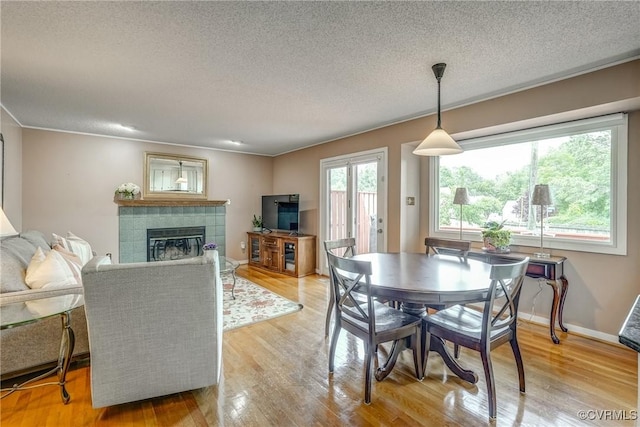 2711 Robson Ct, Henrico, VA 23233 - dining area with light wood finished floors, a tiled fireplace, and a textured ceiling
