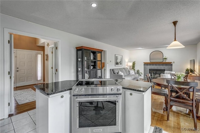 2711 Robson Ct, Henrico, VA 23233 - kitchen with stainless steel range with electric cooktop, a tile fireplace, decorative light fixtures, a center island, and a textured ceiling