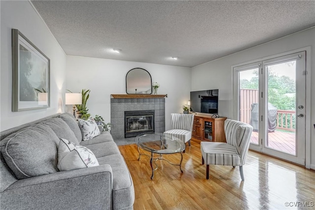 2711 Robson Ct, Henrico, VA 23233 - living room featuring a tile fireplace, light wood-type flooring, and a textured ceiling