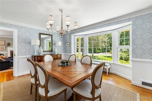 8950 Bellefonte Rd, Henrico, VA 23229 - dining space featuring crown molding, a chandelier, wallpapered walls, light wood finished floors, and a wainscoted wall