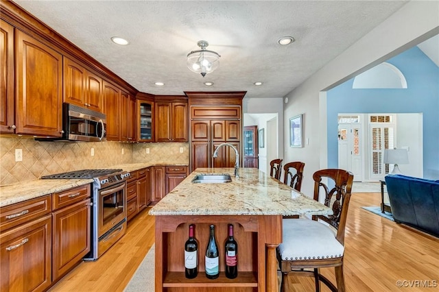 8467 Wendellshire Way, Mechanicsville, VA 23111 - kitchen with appliances with stainless steel finishes, a kitchen bar, light wood finished floors, tasteful backsplash, and light stone counters