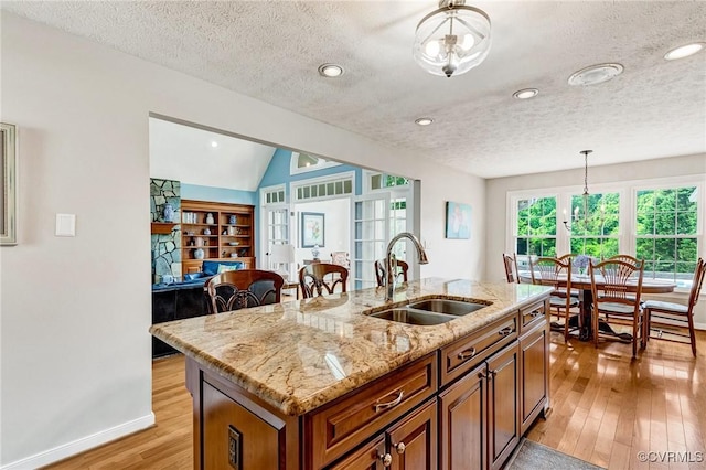 8467 Wendellshire Way, Mechanicsville, VA 23111 - kitchen with brown cabinetry, light wood-style flooring, hanging light fixtures, a textured ceiling, and light stone counters