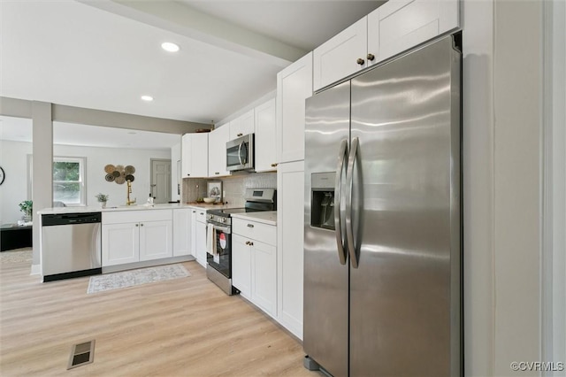 808 Penniman Rd, Williamsburg, VA 23185 - kitchen featuring appliances with stainless steel finishes, light countertops, white cabinetry, light wood-type flooring, and decorative backsplash