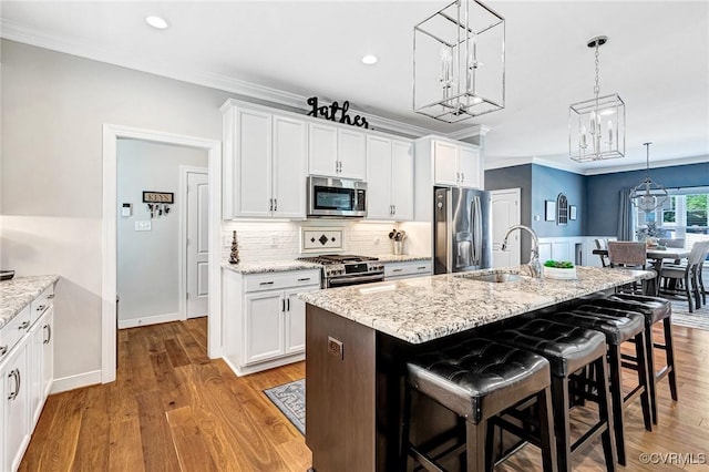 9401 Alsace Ct, Mechanicsville, VA 23116 - kitchen with appliances with stainless steel finishes, a chandelier, a kitchen bar, a kitchen island with sink, and white cabinetry