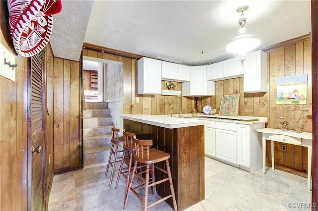1600 Donora Ct, Henrico, VA 23229 - kitchen featuring wooden walls, a breakfast bar, white cabinetry, light countertops, and stovetop