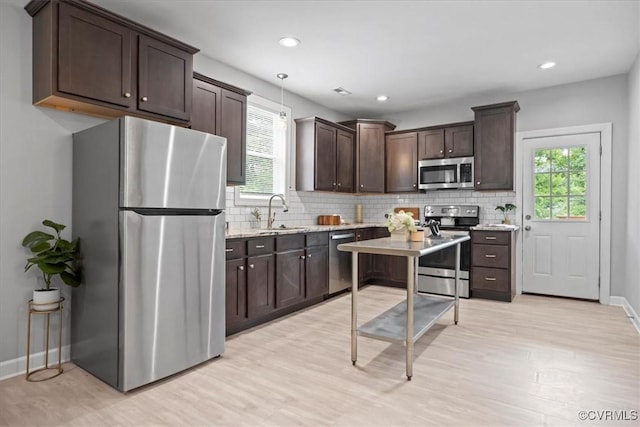 1808 N 20th St, Richmond, VA 23223 - kitchen with stainless steel appliances, dark brown cabinetry, decorative backsplash, light wood-style floors, and light stone countertops
