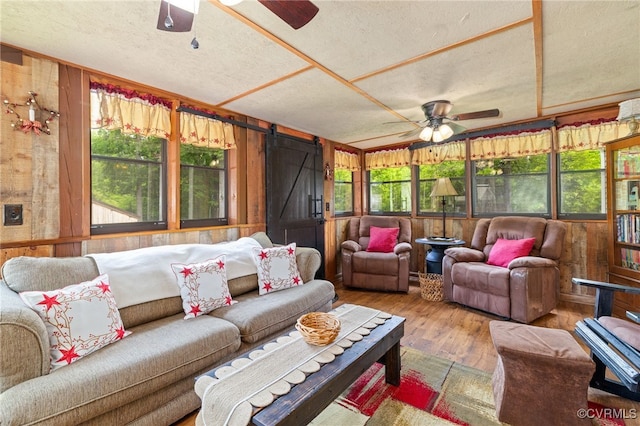 14231 Dykeland Rd, Amelia Courthouse, VA 23002 - living area with a ceiling fan, wooden walls, a textured ceiling, wood finished floors, and a barn door