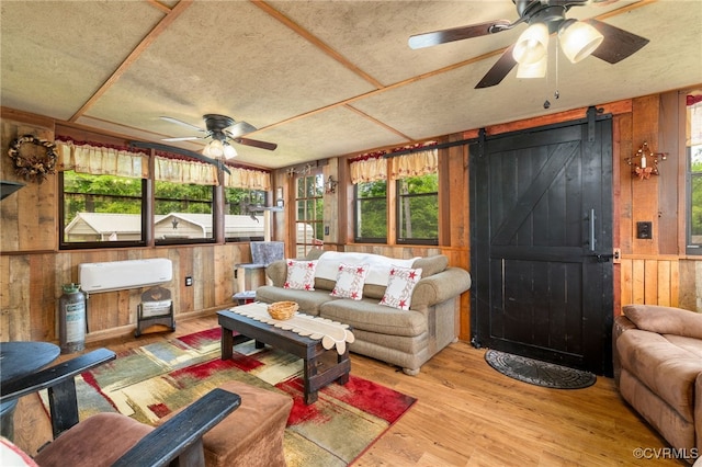 14231 Dykeland Rd, Amelia Courthouse, VA 23002 - living area with wood walls, ceiling fan, a barn door, and wood finished floors