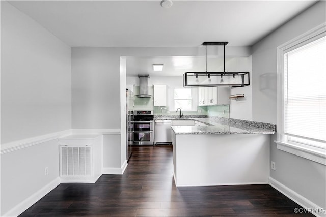 2149 Park Ln, Henrico, VA 23230 - kitchen featuring appliances with stainless steel finishes, wall chimney exhaust hood, a peninsula, white cabinets, and dark wood finished floors