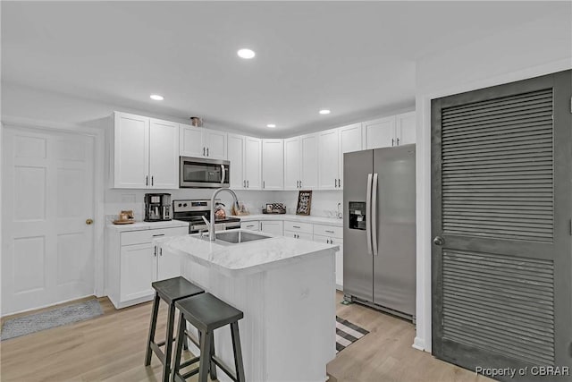 7284 Farinholt St, Gloucester, VA 23061 - kitchen with appliances with stainless steel finishes, light wood-style floors, white cabinets, a center island with sink, and recessed lighting