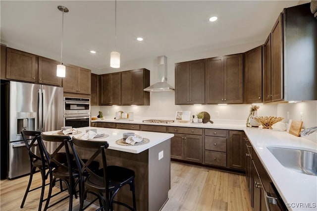 15707 Greenhart Dr, Chesterfield, VA 23832 - kitchen featuring stainless steel appliances, wall chimney exhaust hood, light wood finished floors, a kitchen bar, and light countertops