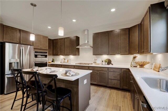 15707 Greenhart Dr, Chesterfield, VA 23832 - kitchen featuring stainless steel appliances, wall chimney exhaust hood, light wood finished floors, a kitchen bar, and light countertops
