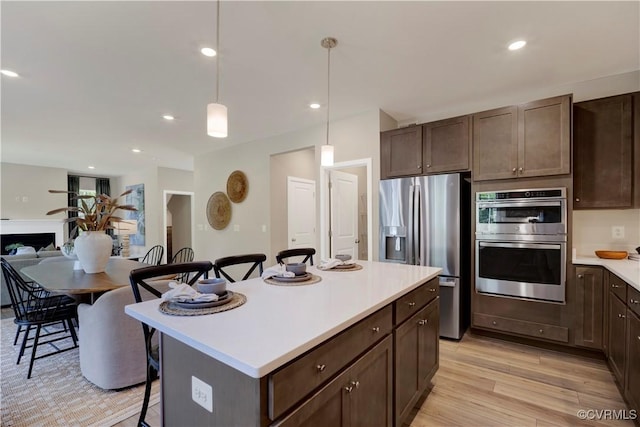 15707 Greenhart Dr, Chesterfield, VA 23832 - kitchen featuring stainless steel appliances, a breakfast bar area, light countertops, dark brown cabinetry, and light wood-style flooring