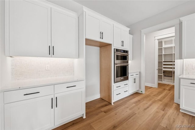 5-6 Pocahontas Trl, Providence Forge, VA 23089 - kitchen featuring stainless steel double oven, backsplash, light wood-type flooring, light countertops, and white cabinetry