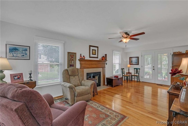 6661 Powhatan Dr, Hayes, VA 23072 - living area featuring a fireplace with flush hearth, ceiling fan, light wood finished floors, and french doors