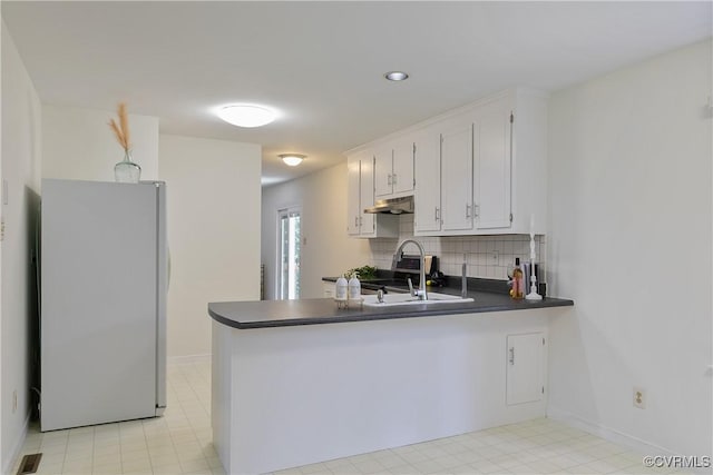 7107 Port Side Dr, Chesterfield, VA 23112 - kitchen with freestanding refrigerator, under cabinet range hood, dark countertops, a peninsula, and decorative backsplash