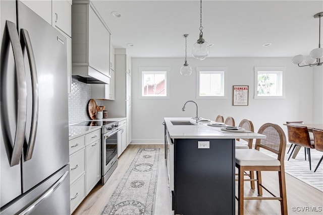 1823 W Cary St Unit A, Richmond, VA 23220 - kitchen with appliances with stainless steel finishes, a kitchen bar, a kitchen island with sink, light countertops, and light wood finished floors