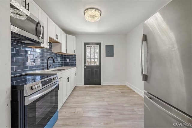1505 Floyd St, Petersburg, VA 23803 - kitchen featuring appliances with stainless steel finishes, decorative backsplash, white cabinetry, light wood-style flooring, and light countertops