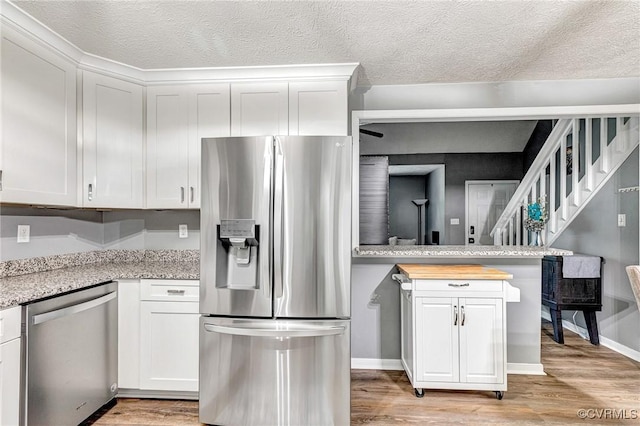 7100 Deer Thicket Dr, Midlothian, VA 23112 - kitchen with stainless steel appliances, light wood finished floors, white cabinetry, and a textured ceiling