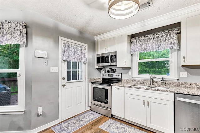 7100 Deer Thicket Dr, Midlothian, VA 23112 - kitchen featuring stainless steel appliances, wood finished floors, white cabinetry, light stone countertops, and a textured ceiling