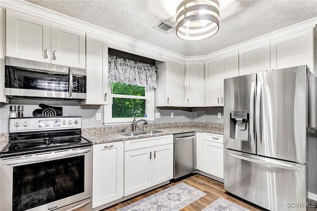 7100 Deer Thicket Dr, Midlothian, VA 23112 - kitchen featuring appliances with stainless steel finishes, light wood-type flooring, white cabinets, a textured ceiling, and light stone counters