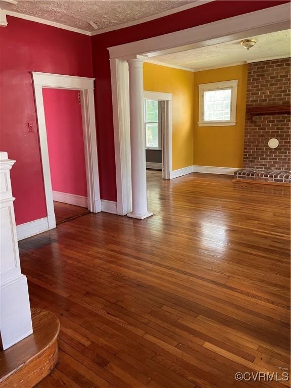 2214 2nd Ave, Richmond, VA 23222 - unfurnished living room featuring decorative columns, crown molding, healthy amount of natural light, wood-type flooring, and a textured ceiling