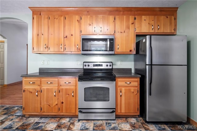 14560 Meade Rd, Amelia, VA 23002 - kitchen with stainless steel appliances, dark countertops, arched walkways, and brown cabinets
