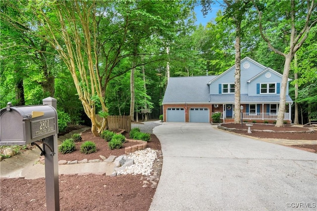 2801 Starling Dr, Williamsburg, VA 23185 - view of front facade featuring covered porch, a garage, driveway, and view of scattered trees