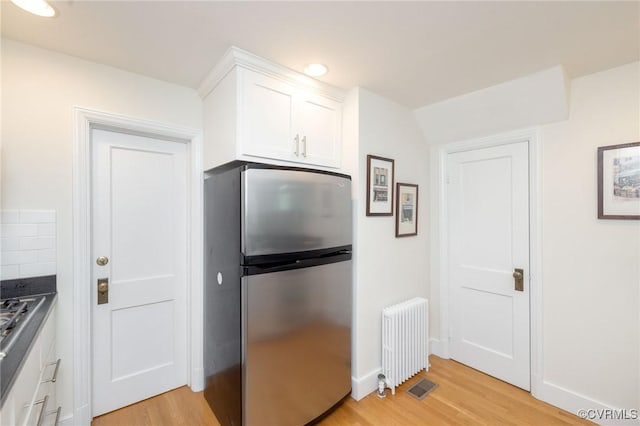 4024 W Grace St, Richmond, VA 23230 - kitchen featuring freestanding refrigerator, radiator heating unit, light wood-style flooring, white cabinets, and recessed lighting