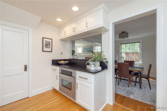 4024 W Grace St, Richmond, VA 23230 - kitchen with stainless steel oven, light wood-style floors, dark countertops, white cabinets, and recessed lighting